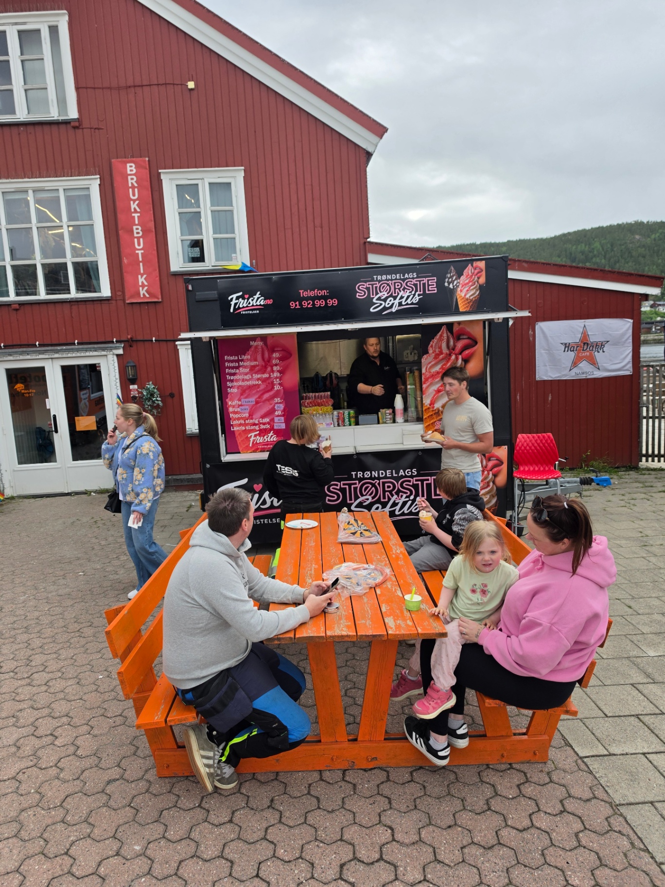 Gjester sitter ved bordet foran Frista-standen og koser seg